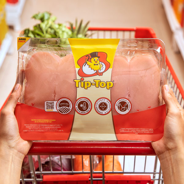 Bandeja de pechuga - Pollo TipTop Manos de mujer en el carrito del supermercado con una bandeja de pechugas de Pollo Tip-Top.